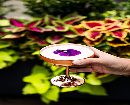 Cocktail in front of flowers| Refinery Rooftop